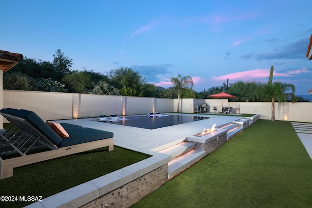 pool at dusk with a fire pit and a patio area