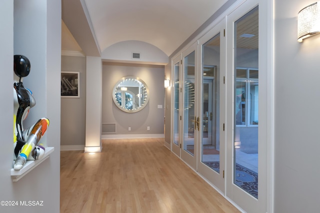 corridor featuring light hardwood / wood-style flooring, lofted ceiling, brick ceiling, and french doors