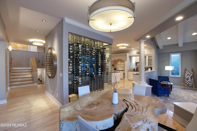 wine cellar featuring ornate columns, crown molding, and light hardwood / wood-style flooring