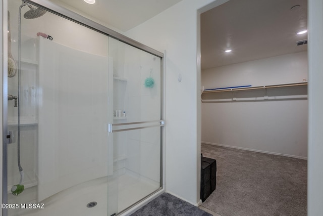 bathroom featuring a spacious closet, a stall shower, and visible vents