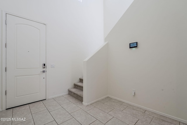 entrance foyer featuring light tile patterned floors, baseboards, and stairway