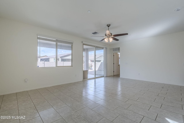 unfurnished room with a ceiling fan, visible vents, baseboards, and light tile patterned flooring