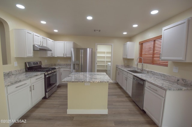 kitchen featuring appliances with stainless steel finishes, sink, light hardwood / wood-style flooring, a center island, and white cabinetry