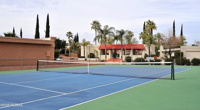 view of tennis court featuring community basketball court and fence