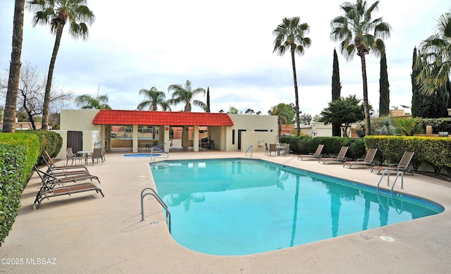 pool featuring fence, a community hot tub, and a patio area