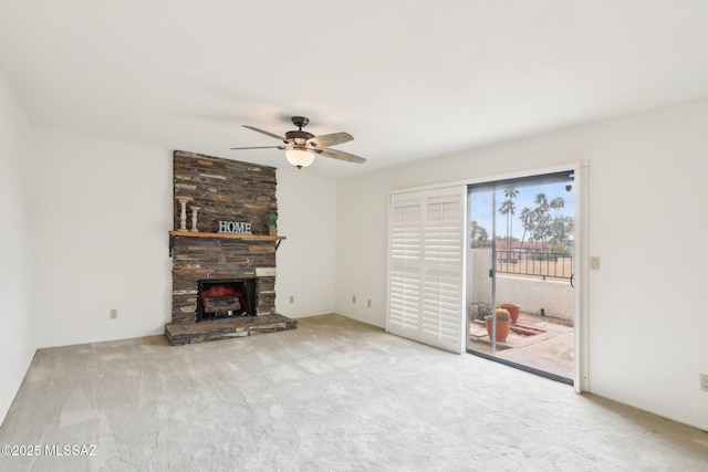 unfurnished living room with carpet, a stone fireplace, and a ceiling fan