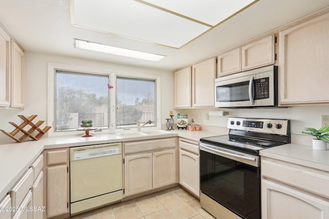 kitchen with light brown cabinetry, appliances with stainless steel finishes, light countertops, and a sink