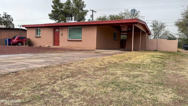 ranch-style house with cooling unit, a carport, and a front lawn