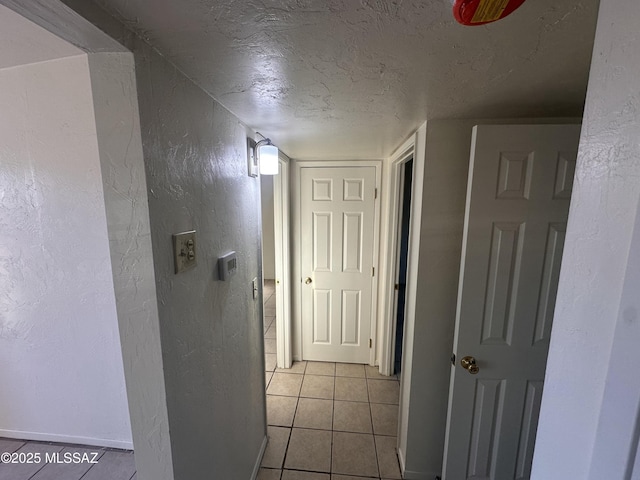 corridor with a textured ceiling and light tile patterned floors