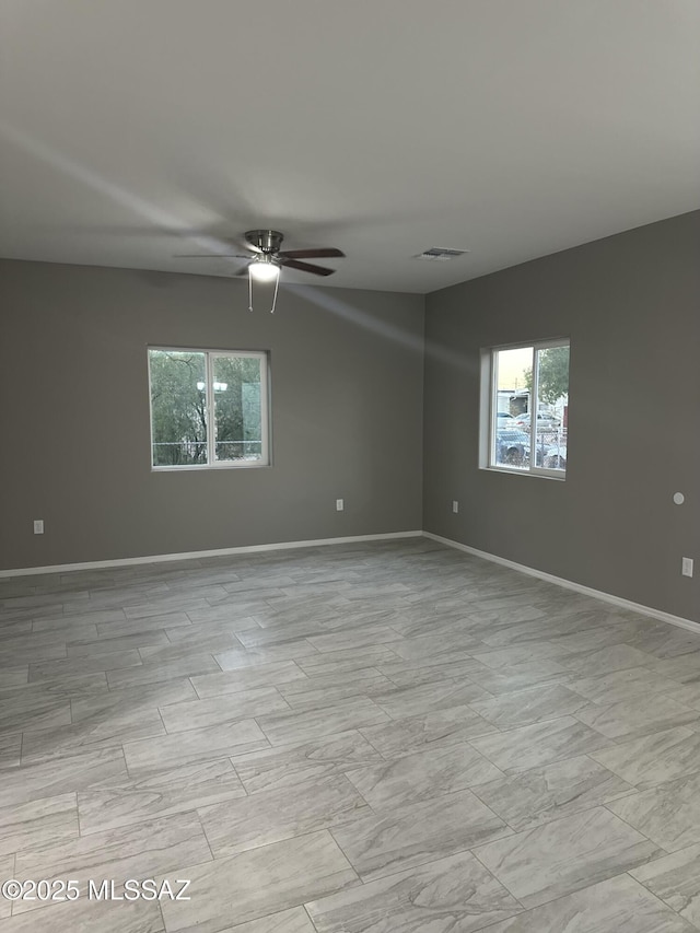 unfurnished room featuring ceiling fan and a wealth of natural light