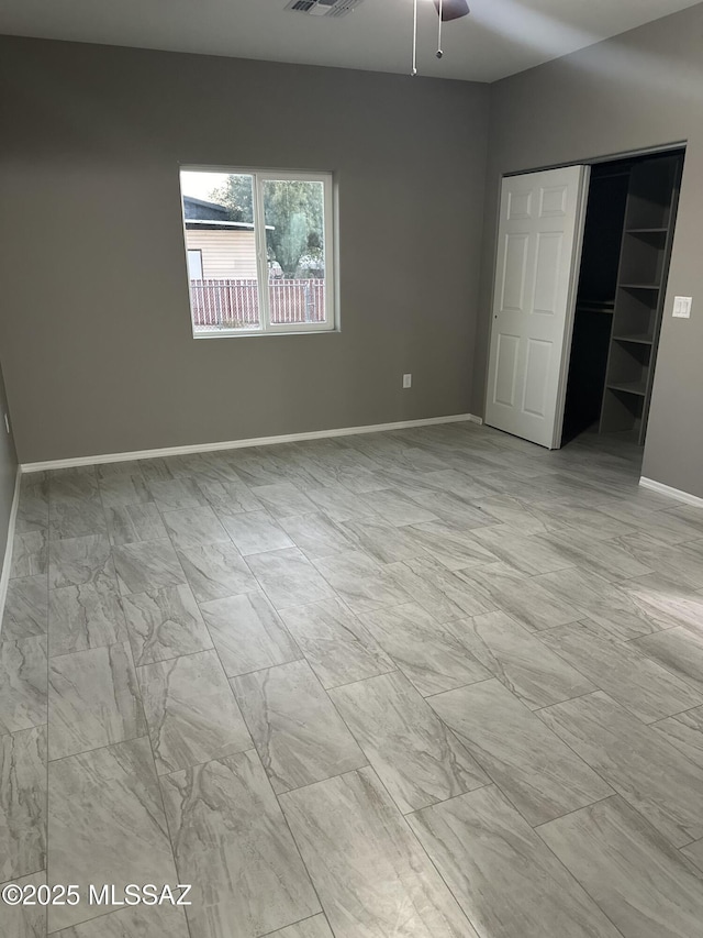 unfurnished bedroom with a spacious closet, a closet, and ceiling fan