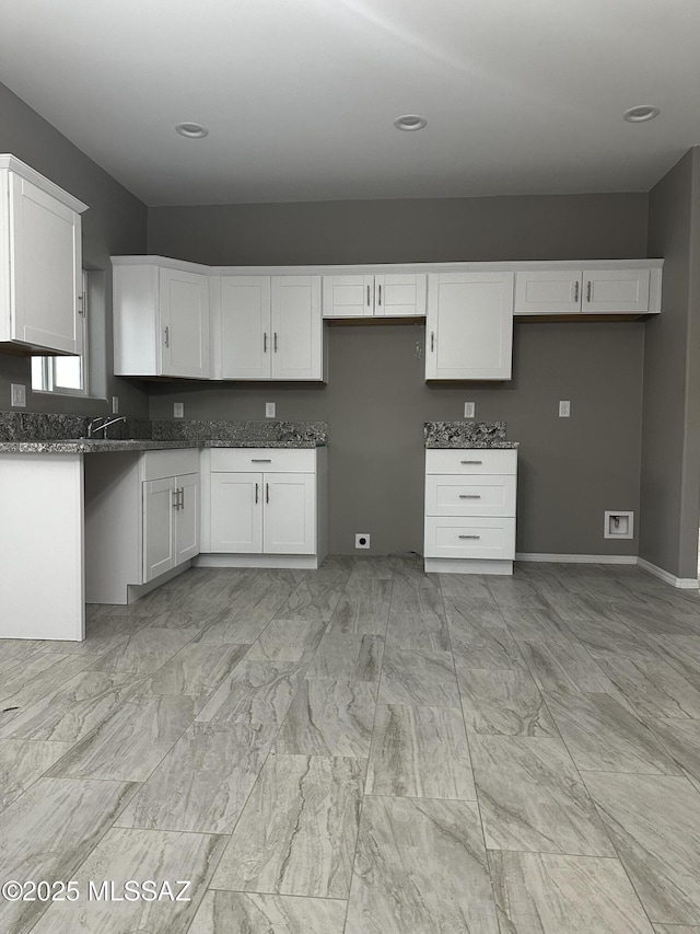 kitchen with white cabinetry and dark stone counters