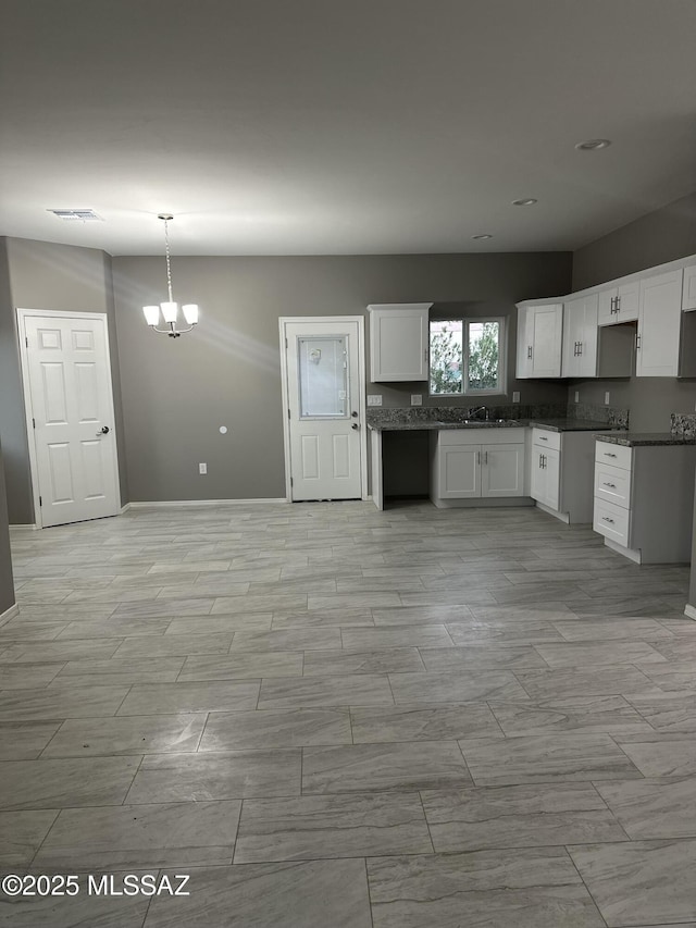 kitchen featuring white cabinetry, a chandelier, hanging light fixtures, and sink