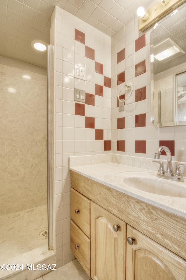 bathroom featuring vanity, a shower with shower door, and tile walls