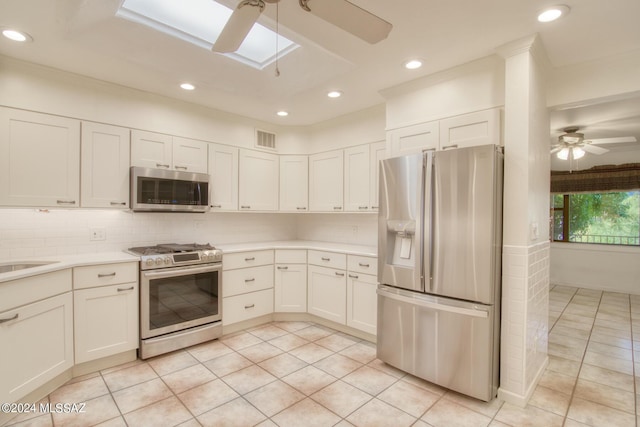 kitchen featuring light tile patterned floors, decorative backsplash, stainless steel appliances, and white cabinets