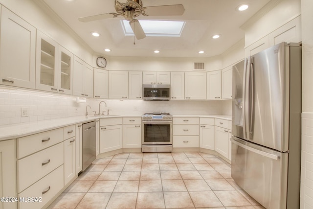 kitchen featuring sink, ceiling fan, a skylight, stainless steel appliances, and light tile patterned flooring