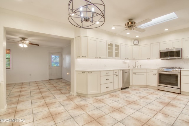 kitchen with ceiling fan with notable chandelier, sink, white cabinets, hanging light fixtures, and stainless steel appliances