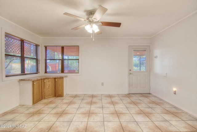 spare room with ceiling fan, ornamental molding, and light tile patterned floors