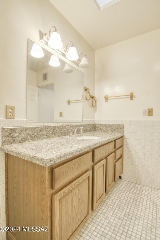 bathroom featuring vanity, tile patterned flooring, and tile walls