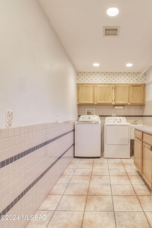 laundry area featuring cabinets, light tile patterned flooring, tile walls, and washer and clothes dryer