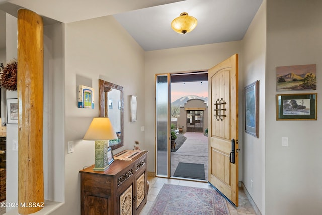 foyer featuring arched walkways, baseboards, and light tile patterned floors