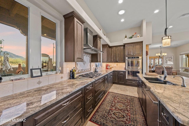 kitchen featuring stainless steel appliances, visible vents, dark brown cabinets, wall chimney range hood, and decorative backsplash