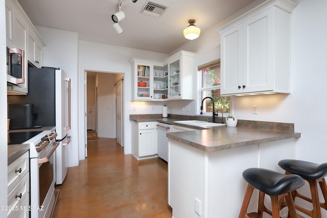 kitchen featuring concrete floors, kitchen peninsula, sink, white cabinetry, and stainless steel appliances