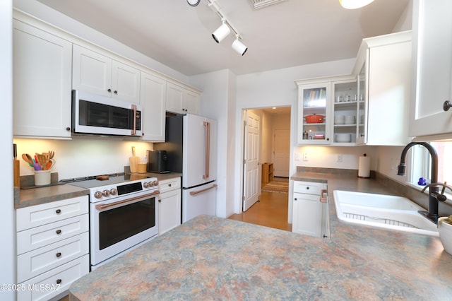 kitchen featuring sink, white cabinets, rail lighting, and high quality appliances