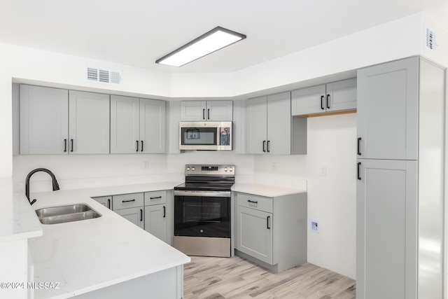 kitchen with gray cabinets, sink, and appliances with stainless steel finishes