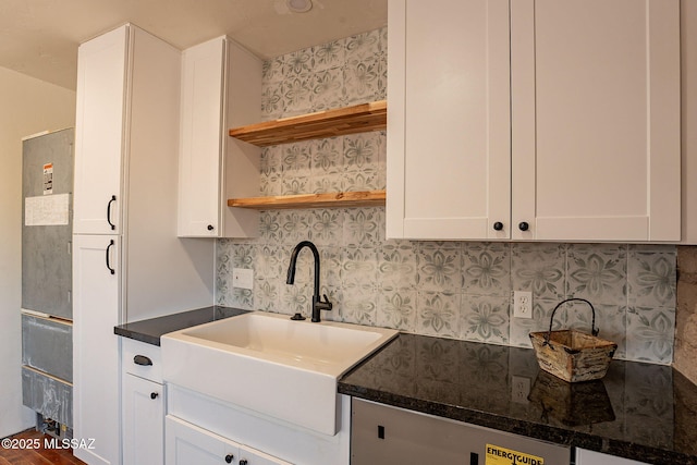 kitchen with white cabinetry, sink, dark stone countertops, and decorative backsplash