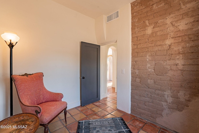 living area featuring light tile patterned floors and brick wall