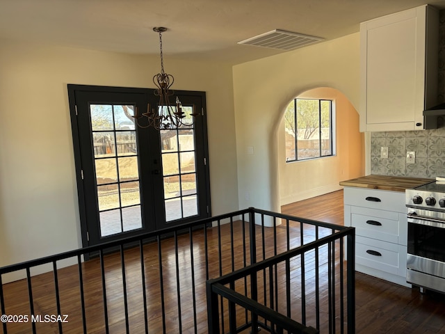 interior space featuring wood counters, stainless steel range oven, white cabinetry, dark hardwood / wood-style floors, and pendant lighting