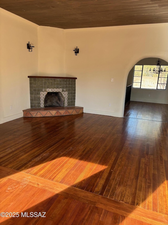 unfurnished living room with a tiled fireplace and wood-type flooring