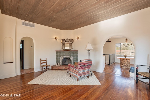 living room with a notable chandelier, hardwood / wood-style floors, wooden ceiling, and a fireplace