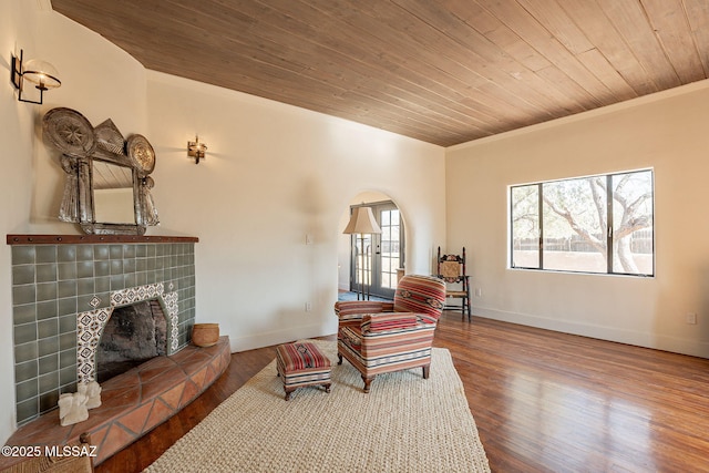 sitting room with hardwood / wood-style floors, ornamental molding, wooden ceiling, and a tile fireplace