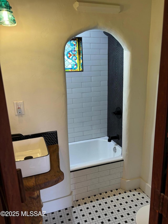 full bathroom featuring tile patterned flooring, sink, tiled shower / bath combo, and toilet