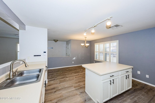 kitchen with white cabinetry, sink, dark wood-type flooring, decorative light fixtures, and a kitchen island