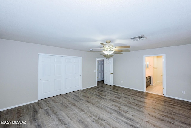 unfurnished bedroom featuring ensuite bath, ceiling fan, a closet, and light wood-type flooring