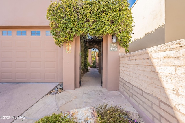 view of exterior entry featuring a garage and stucco siding