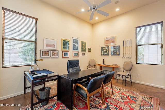 office area featuring ceiling fan, dark tile patterned floors, and a high ceiling