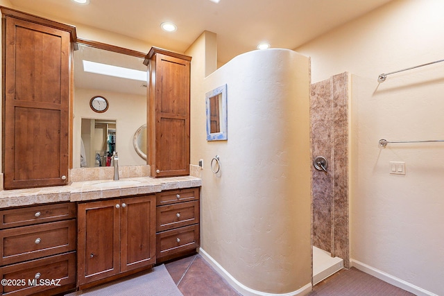 bathroom with recessed lighting, baseboards, vanity, and a walk in shower