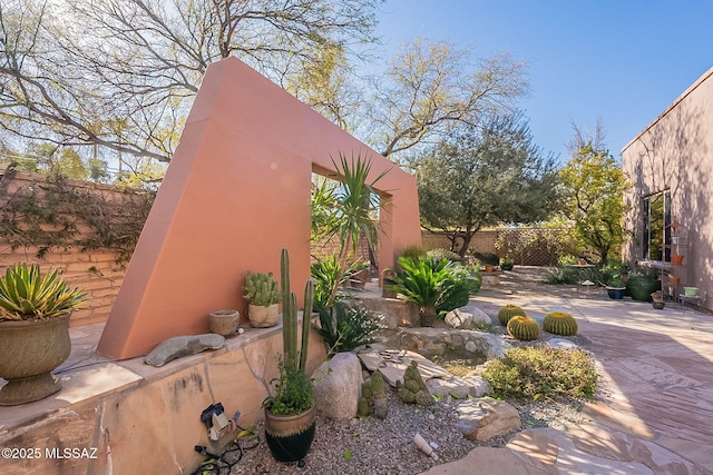 view of side of property with stucco siding, a patio, and fence