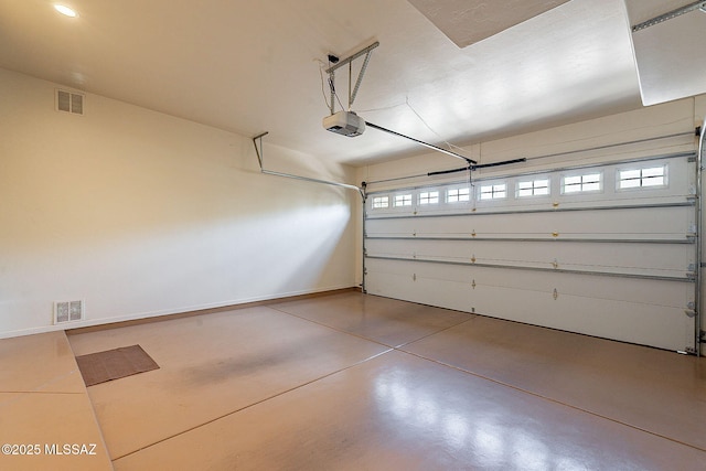 garage featuring visible vents, a garage door opener, and baseboards