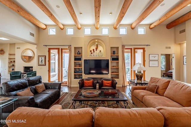 living room featuring hardwood / wood-style flooring, built in shelves, plenty of natural light, and a towering ceiling