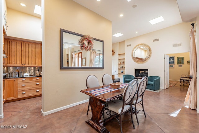 dining area with concrete flooring, a towering ceiling, and built in features