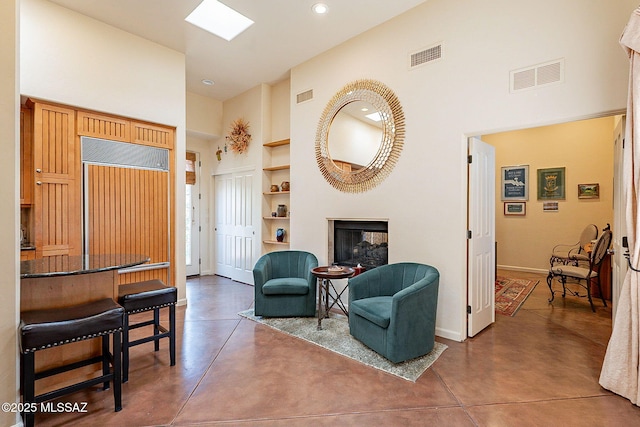 sitting room featuring built in shelves, concrete flooring, and a high ceiling