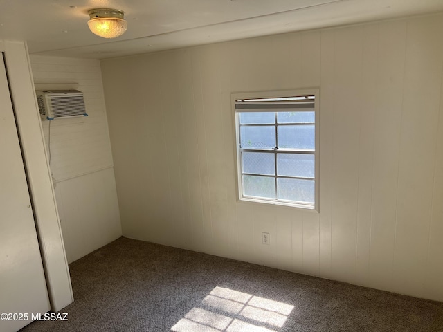 carpeted empty room with an AC wall unit and wood walls