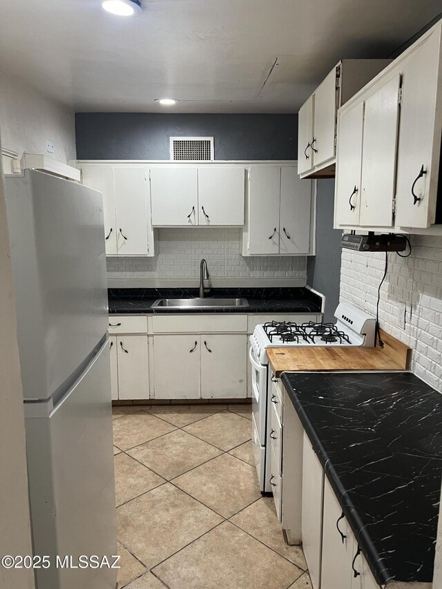 kitchen featuring light tile patterned floors, backsplash, white cabinetry, and gas range gas stove