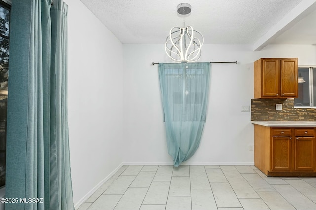 unfurnished dining area featuring light tile patterned floors, a textured ceiling, and an inviting chandelier