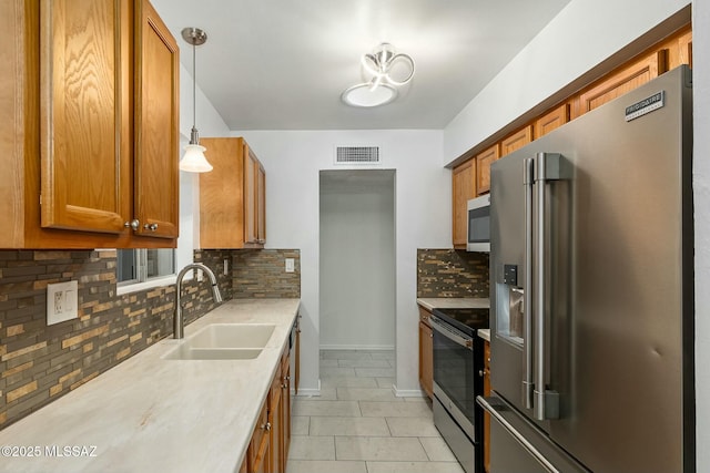 kitchen with pendant lighting, sink, decorative backsplash, and appliances with stainless steel finishes